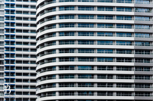 Minimalist architectural detail showing repeating geometric lines of glass windows on a modern skyscraper in Yokohama, Japan.