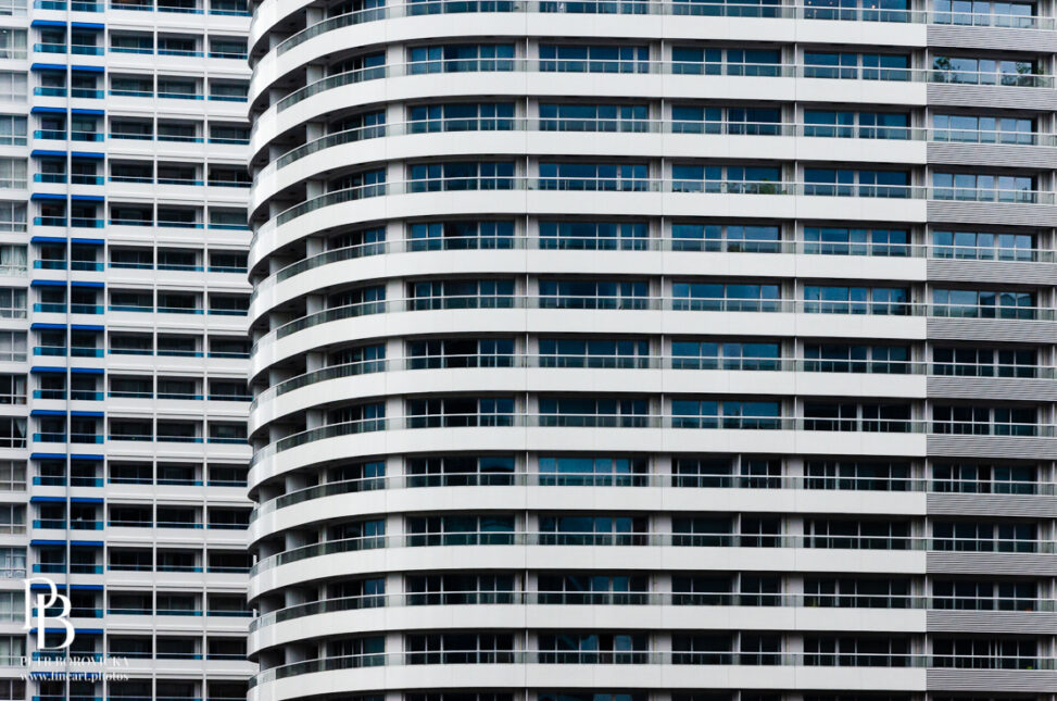 Minimalist architectural detail showing repeating geometric lines of glass windows on a modern skyscraper in Yokohama, Japan.