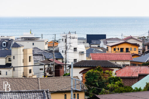 Minimalist view of the Kamakura town skyline, featuring clean architectural lines against a vast, empty ocean and sky.