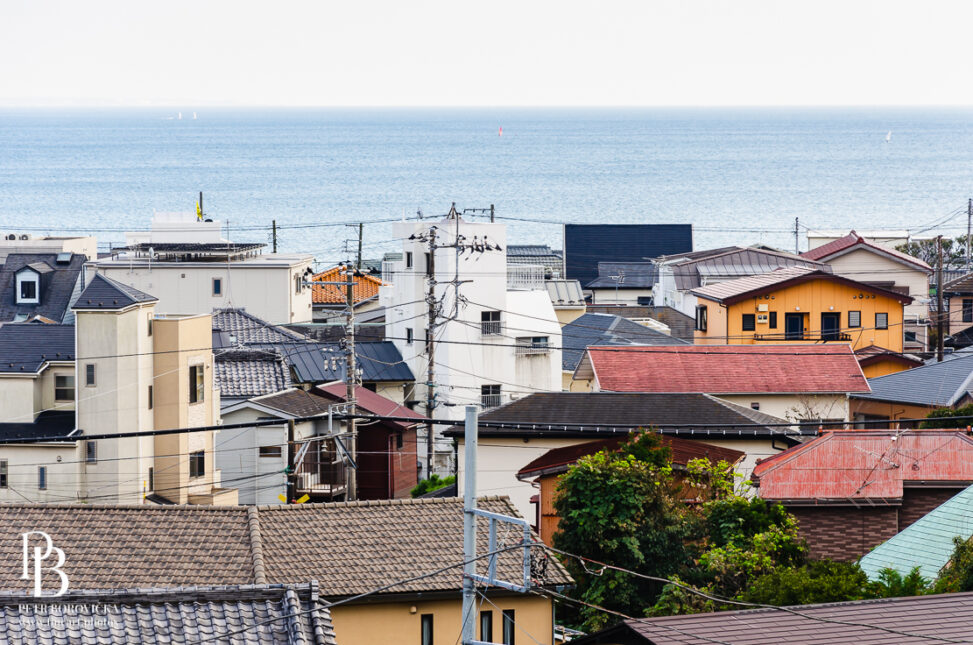 Minimalist view of the Kamakura town skyline, featuring clean architectural lines against a vast, empty ocean and sky.