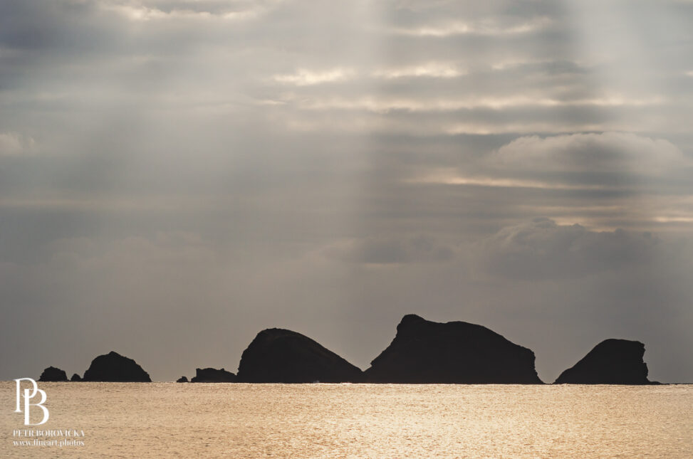 Stark coastal cliffs meeting the calm Pacific Ocean in Okinawa beneath a clear, expansive sky.