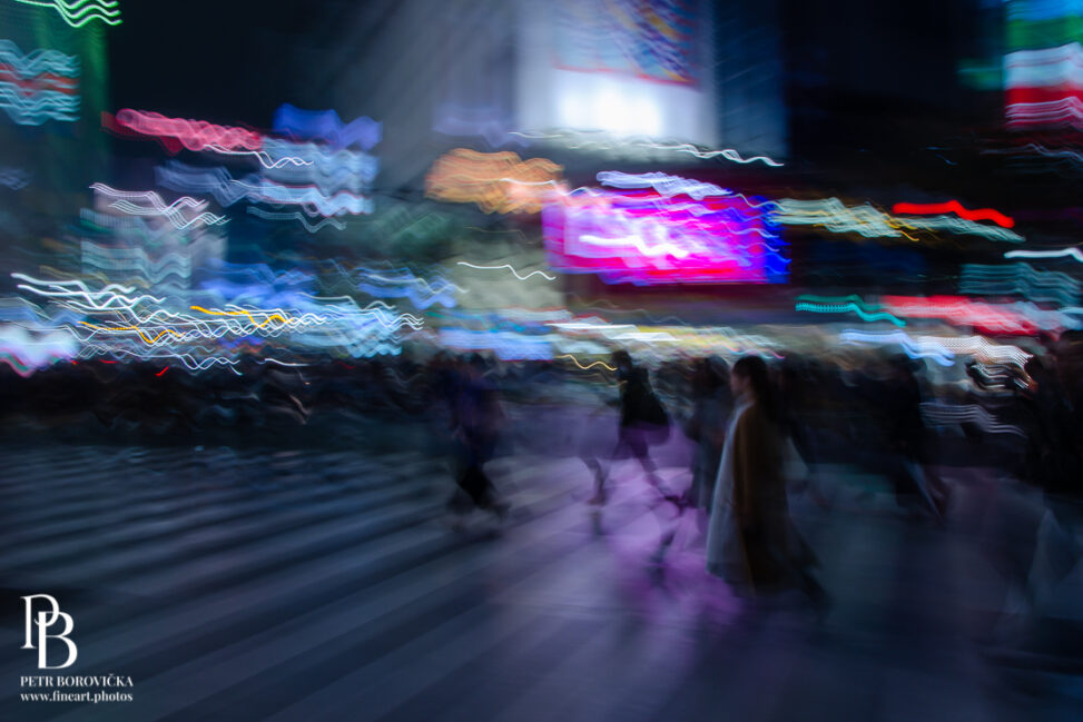 Abstract, dreamy color long exposure of the Shibuya crossing in Tokyo at night, featuring blurred figures moving against a backdrop of glowing neon city lights.
